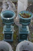 A PAIR OF SMALL GREEN PAINTED CAST IRON CAMPANA GARDEN URNS, with foliate decoration, twin handles