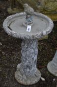 A COMPOSITE TREE EFFECT BIRD BATH, with a bird to the top, on a separate base, diameter 48cm x
