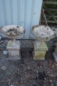 A PAIR OF WEATHERED RECONSTITUTED STONE CAMPANA GARDEN URNS on a separate square plinth base,