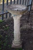 A WEATHERED COMPOSITE BIRD BATH on a Corinthian foliate column, diameter 41cm x height 84cm