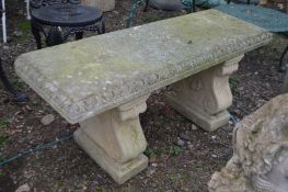 A WEATHERED COMPOSITE GARDEN BENCH on a pair of separate bases width 120cm x depth 42cm x height