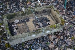 A RECTANGULAR RECONSTITUTED STONE TROUGH raised on twin supports, width 83cm x depth 47cm x height