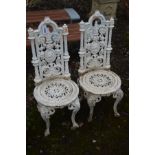 A PAIR OF HEAVY CAST IRON CHAIRS, each with high backs, with curved cresting rails, pierced floral