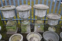 A SET OF FOUR COMPOSITE URNS, with Acanthus leaf decoration, three urns on separate square