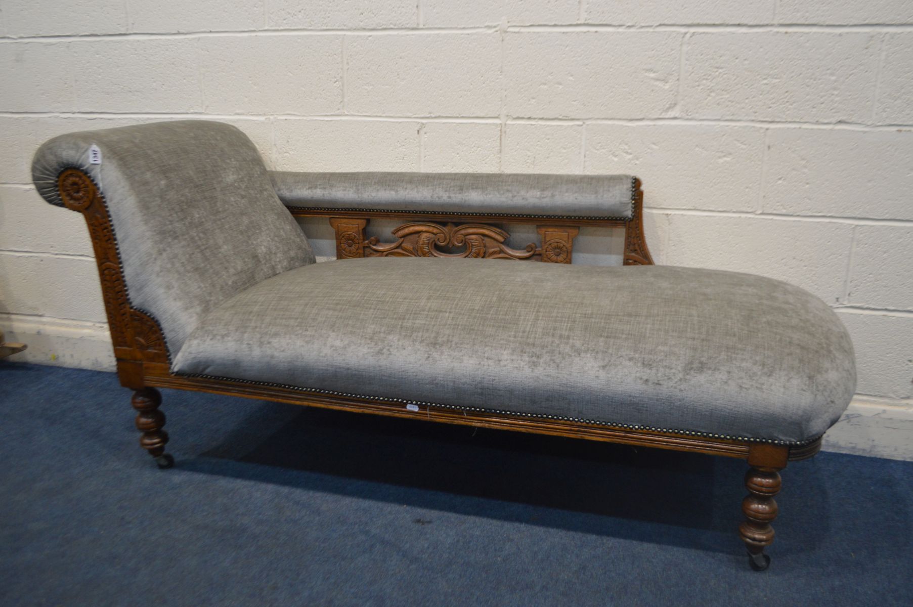 A EDWARDIAN CARVED OAK CHAISE LONGUE, reupholstered in grey, length 177cm