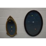 AN ORNATE GILTWOOD OVAL BEVELLED EDGE WALL MIRROR and a mahogany oval wall mirror, 82cm x 57cm (2)