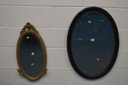 AN ORNATE GILTWOOD OVAL BEVELLED EDGE WALL MIRROR and a mahogany oval wall mirror, 82cm x 57cm (2)