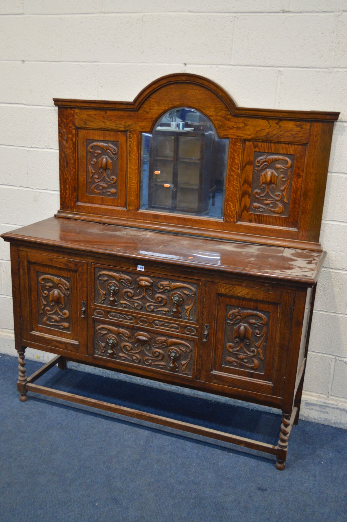 AN EARLY 20TH CENTURY OAK MIRRORBACK SIDEBOARD, with detailed carved panels, barley twist front