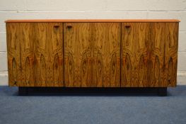 A 1970'S ROSEWOOD THREE DOOR SIDEBOARD, the central door with three internal drawers, on square