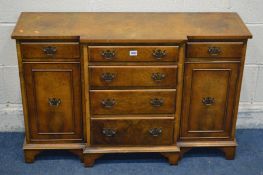 A SMALL REPRODUCTION WALNUT AND CROSSBANDED BREAKFRONT SIDEBOARD with six various drawers and two