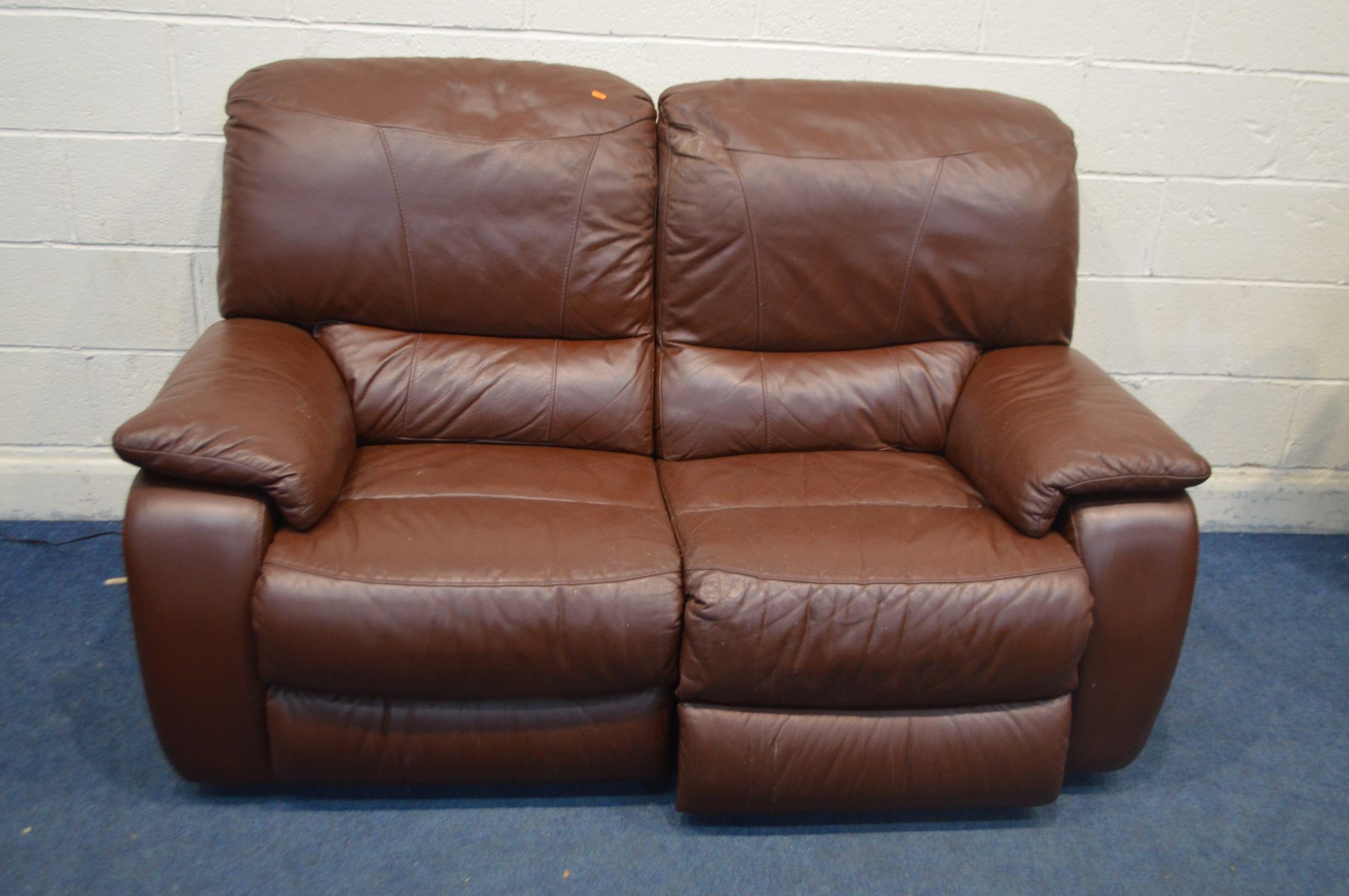 A BURGUNDY LEATHER TWO SEATER ELECTRIC RECLINING SOFA, width 166cm and an ottoman pouffe (PAT pass