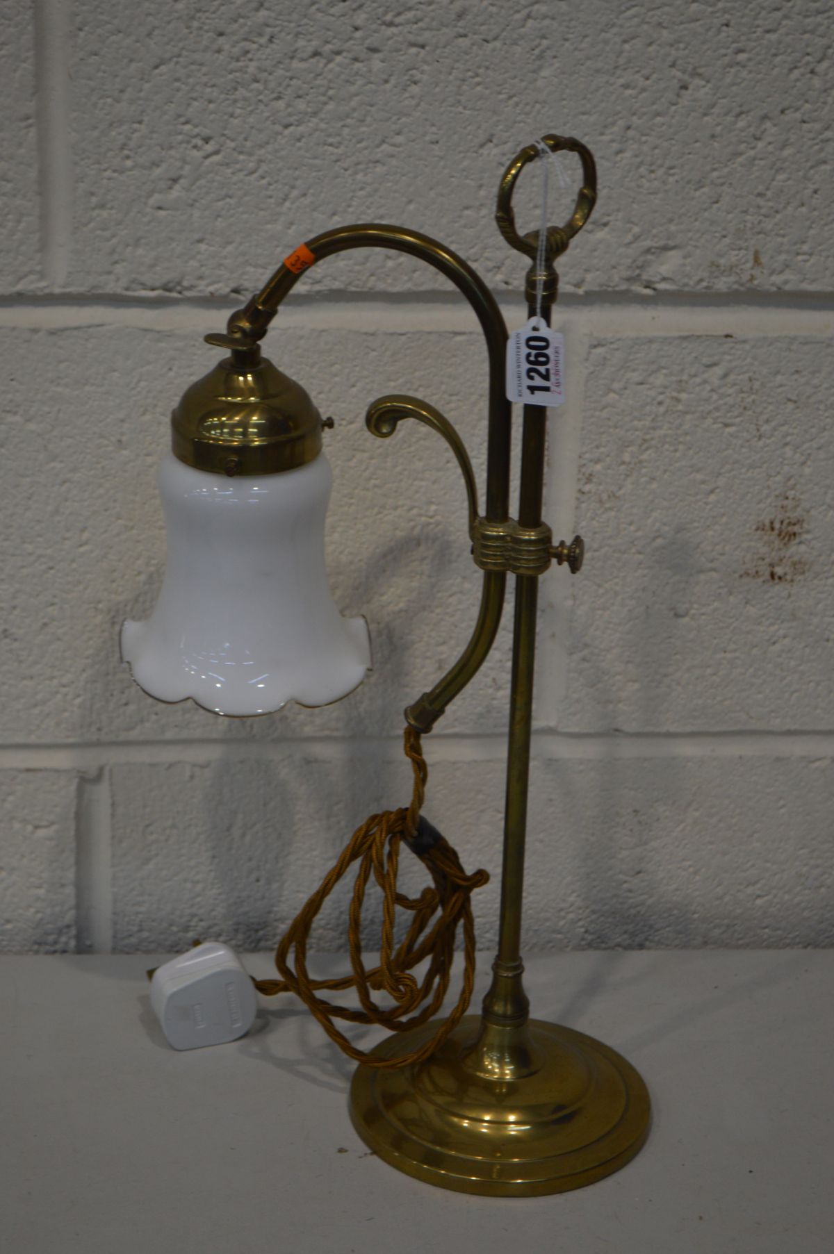 A BRASS SINGLE BRANCH ADJUSTABLE TABLE LIGHT, with a shaped white glass shade