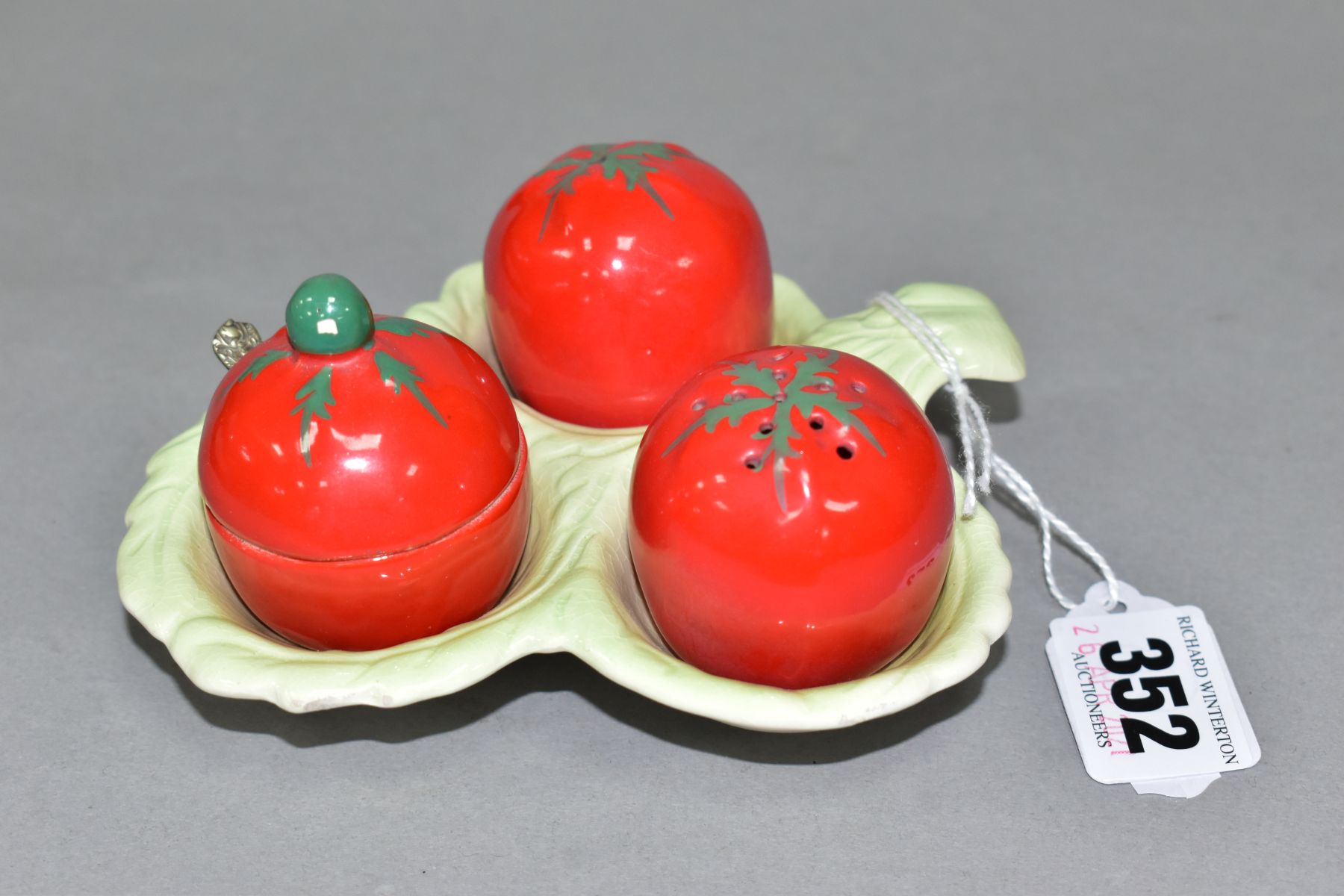 A CARLTON WARE AUSTRALIAN DESIGN CRUET IN THE FORM OF THREE TOMATOES ON A LEAF MOULDED STAND, salt