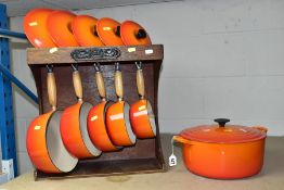 A SET OF FIVE LE CREUSET ORANGE GRADUATED SAUCE PANS, sizes 14, 16, 18, 20 and 22, together with a