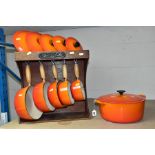 A SET OF FIVE LE CREUSET ORANGE GRADUATED SAUCE PANS, sizes 14, 16, 18, 20 and 22, together with a