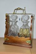 A MODERN MAHOGANY AND BRASS MOUNTED TANTALUS, locked, fitted with two decanters and stoppers,