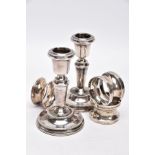 A PAIR OF SILVER DWARF CANDLESTICKS AND THREE NAPKIN RINGS, each candlestick has a round weighted
