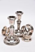 A PAIR OF SILVER DWARF CANDLESTICKS AND THREE NAPKIN RINGS, each candlestick has a round weighted