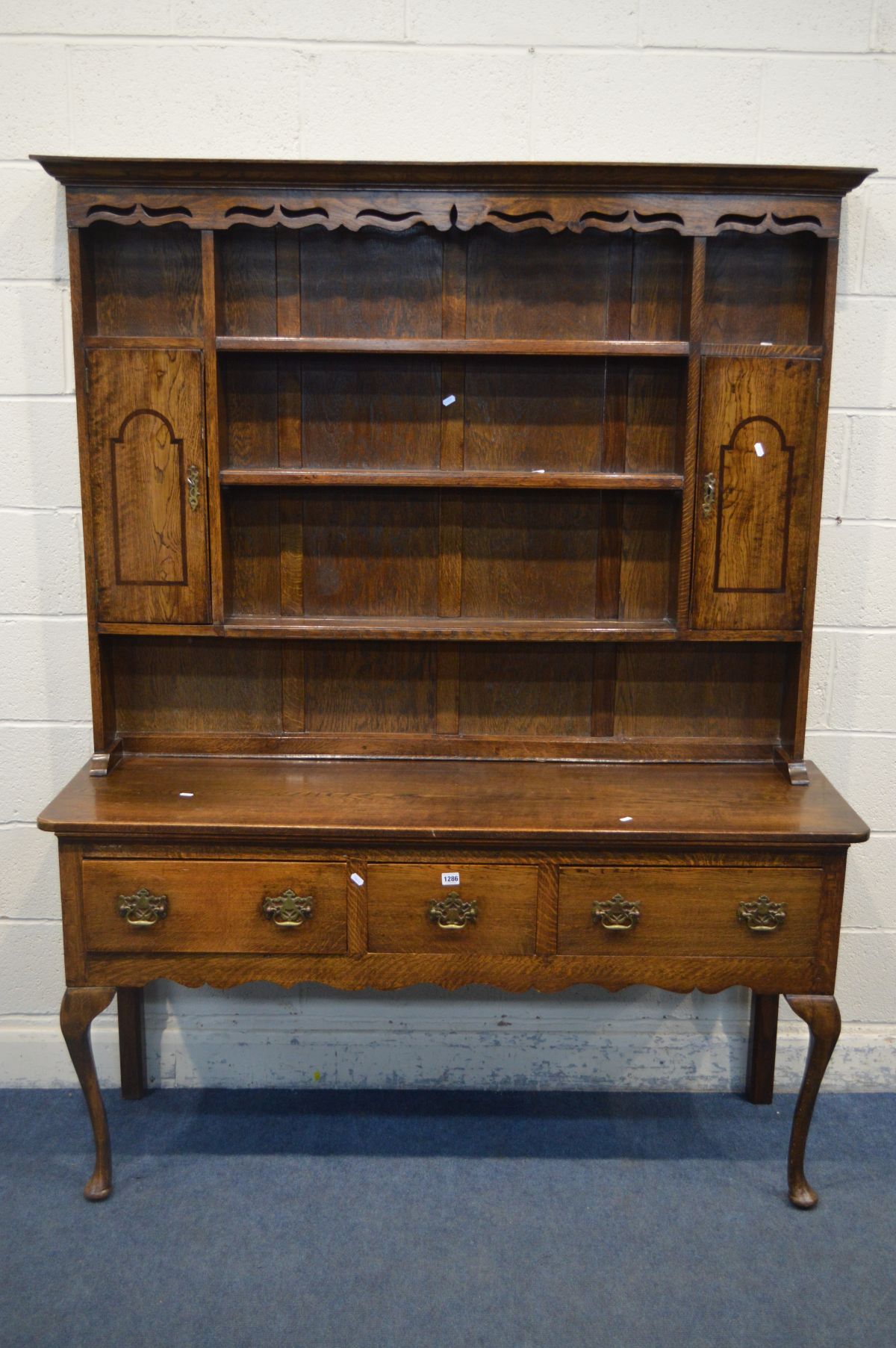 A GEORGE III STYLE OAK DRESSER, the top with a wavy apron to the top, twin single doors, over a base