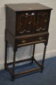 AN EARLY 20TH CENTURY OAK TWO DOOR CABINET, single drawer, on barley twist legs united by