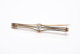 A YELLOW METAL DIAMOND BROOCH, openwork bar brooch set with a round brilliant cut diamond within a