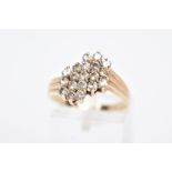 A YELLOW METAL DIAMOND CLUSTER RING, an asymmetrical cluster design with claw set, round brilliant