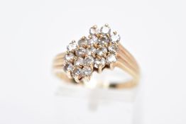 A YELLOW METAL DIAMOND CLUSTER RING, an asymmetrical cluster design with claw set, round brilliant