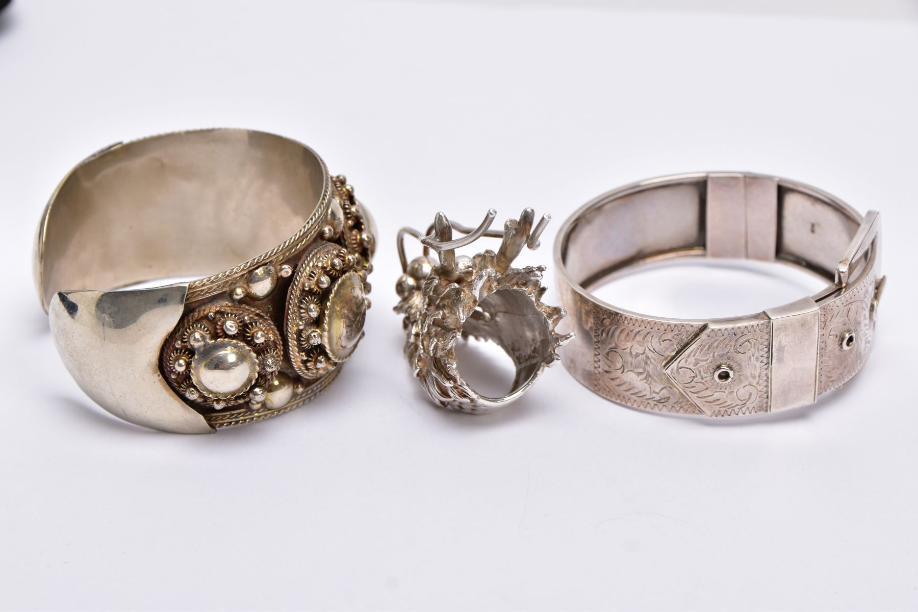 A WHITE METAL BANGLE, CUFF BANGLE AND A RING, the hinged bangle of a belt and buckle design, foliate - Image 3 of 5