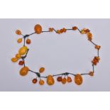 AN AMBER NECKLACE, designed with a mixture of transparent and butterscotch coloured amber in various