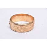 A ROLLED GOLD WIDE BANGLE, hinged bangle with a half engraved foliate design, push pin clasp, fitted