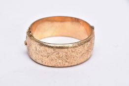 A ROLLED GOLD WIDE BANGLE, hinged bangle with a half engraved foliate design, push pin clasp, fitted