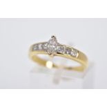 A YELLOW METAL DIAMOND RING, designed with a central raised, marquise cut diamond, flanked with