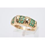 A 14CT GOLD EMERALD RING, designed with three sections each set with two rows of circular cut
