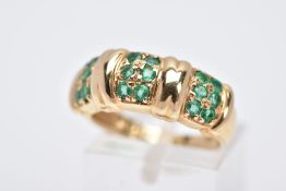 A 14CT GOLD EMERALD RING, designed with three sections each set with two rows of circular cut