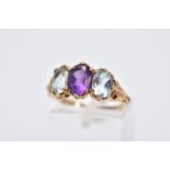 A 9CT GOLD THREE STONE RING, centring on an oval cut amethyst, flanked with two oval cut