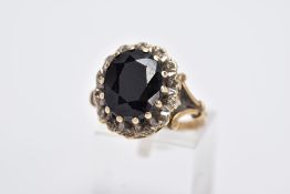A 9CT GOLD SAPPHIRE AND DIAMOND CLUSTER RING, centring on a claw set, oval cut blue sapphire