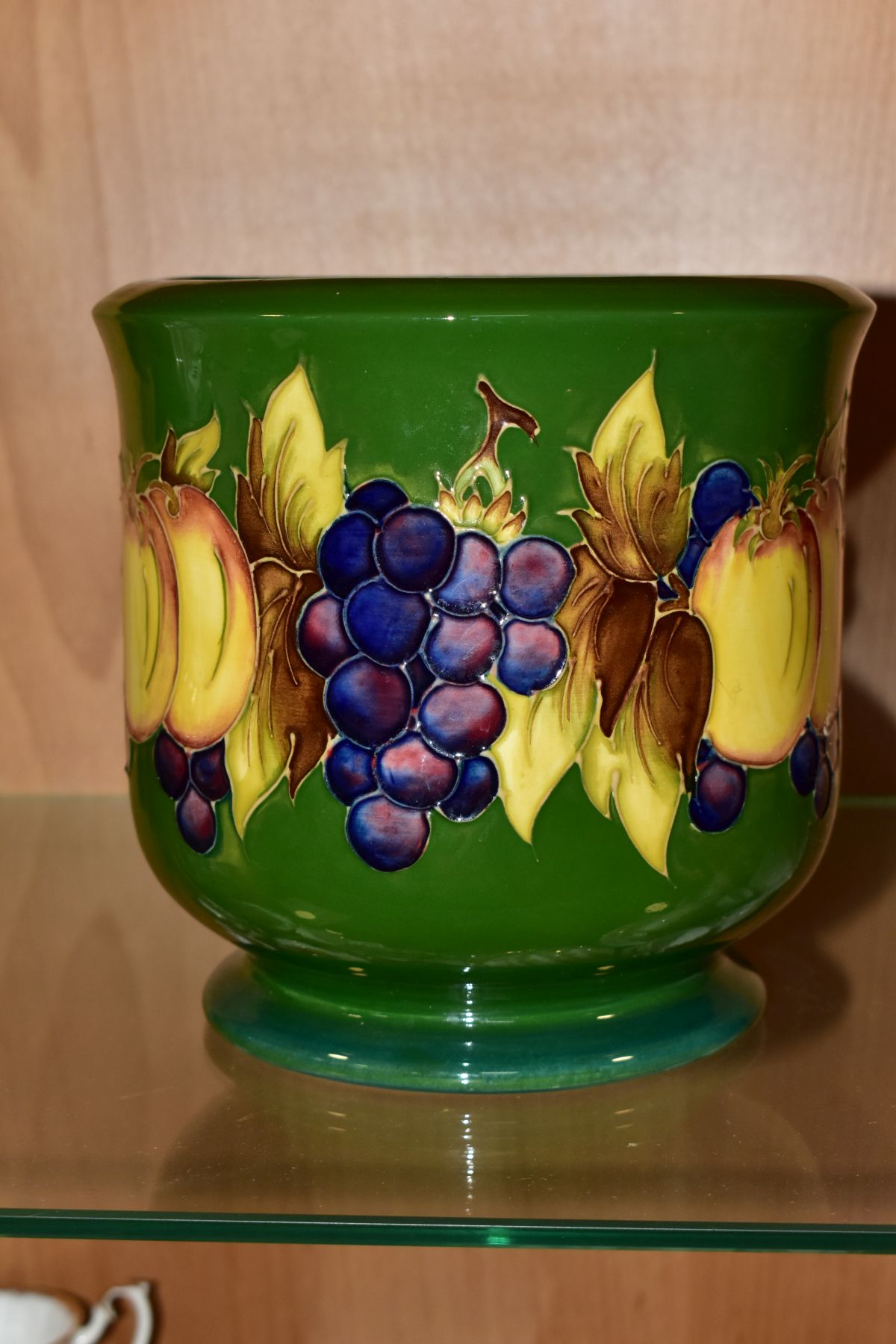 A MOORCROFT POTTERY JARDINIERE DECORATED IN THE FRUIT AND BERRIES PATTERN, on a green ground,