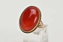 A 9CT GOLD CARNELIAN RING, set with an oval cabochon carnelian, within a collect and rope twist