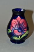 A SMALL MOORCROFT POTTERY BALUSTER VASE, decorated with blue and pink/blue Clematis on a dark blue