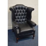 A BLACK FAUX LEATHER BUTTONED WINGBACK ARMCHAIR (this chair does not comply with the Furniture and