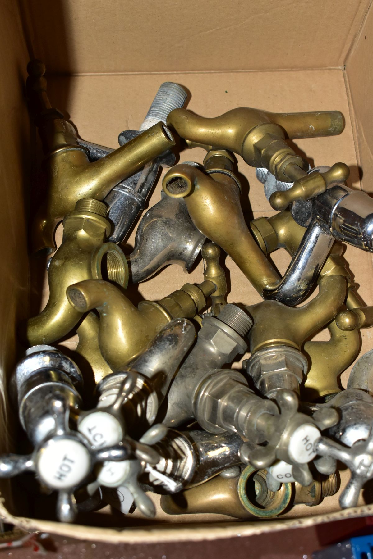 A BOX OF TAPS AND TAP PARTS, including brass taps, stainless steel finished taps, some having