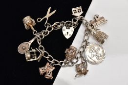 A HEAVY SILVER CHARM BRACELET, suspending eleven charms in forms such as a silver wishing well