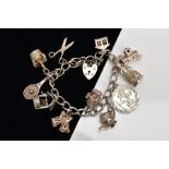 A HEAVY SILVER CHARM BRACELET, suspending eleven charms in forms such as a silver wishing well