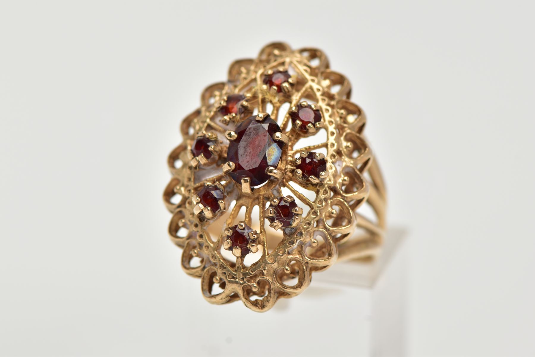 A 9CT GOLD GARNET RING, of an openwork lozenge form, set with a central oval cut garnet and circular