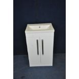 AN AMS PLUMBING WC SINK UNIT with a shallow ceramic sink standing on a white hi gloss two door
