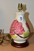A MOORCROFT POTTERY TABLE LAMP DECORATED WITH PINK MAGNOLIA ON A CREAM GROUND, mounted on a circular