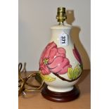 A MOORCROFT POTTERY TABLE LAMP DECORATED WITH PINK MAGNOLIA ON A CREAM GROUND, mounted on a circular
