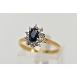 AN 18CT GOLD SAPPHIRE AND DIAMOND CLUSTER RING, centring on an oval cut blue sapphire (possibly