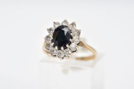 A 9CT GOLD SAPPHIRE CLUSTER RING, centring on an oval cut blue sapphire within a circular cut