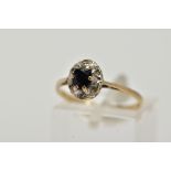 A 9CT GOLD SAPPHIRE AND DIAMOND CLUSTER RING, raised cluster, centring on a claw set, oval cut